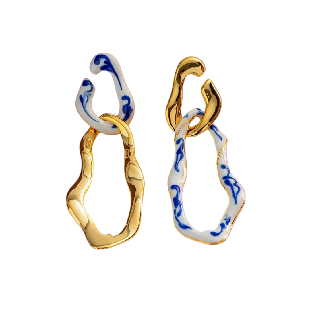 Gold and blue patterned earrings on a purple background
