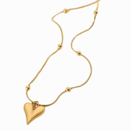 Gold necklace with a heart-shaped pendant on a white background