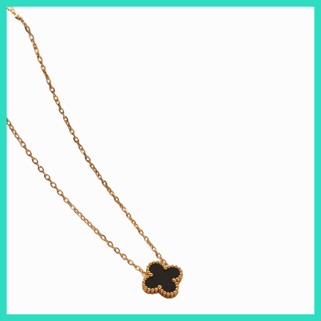 Gold necklace with a black clover-shaped pendant on a white background