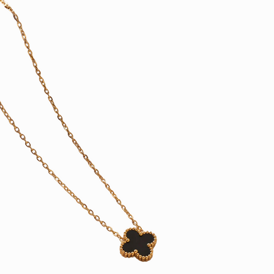 Gold necklace with a black clover-shaped pendant on a white background