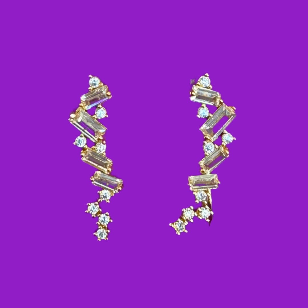 Gold and crystal earrings on a purple background