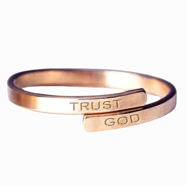 Rose gold ring with 'TRUST GOD' engraving on a white background