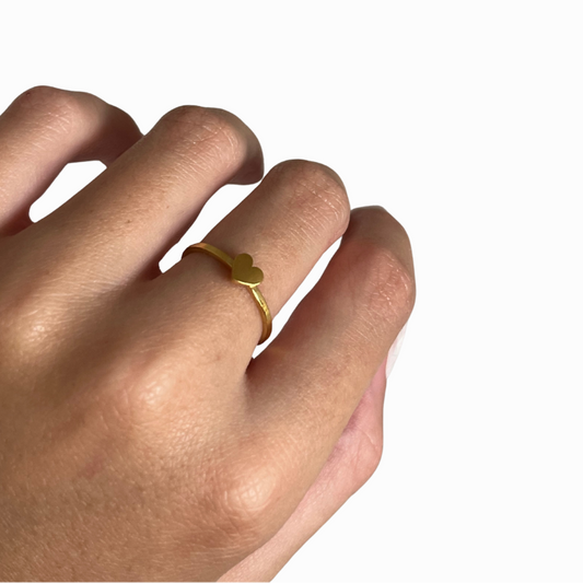 Hand wearing a gold ring on a white background