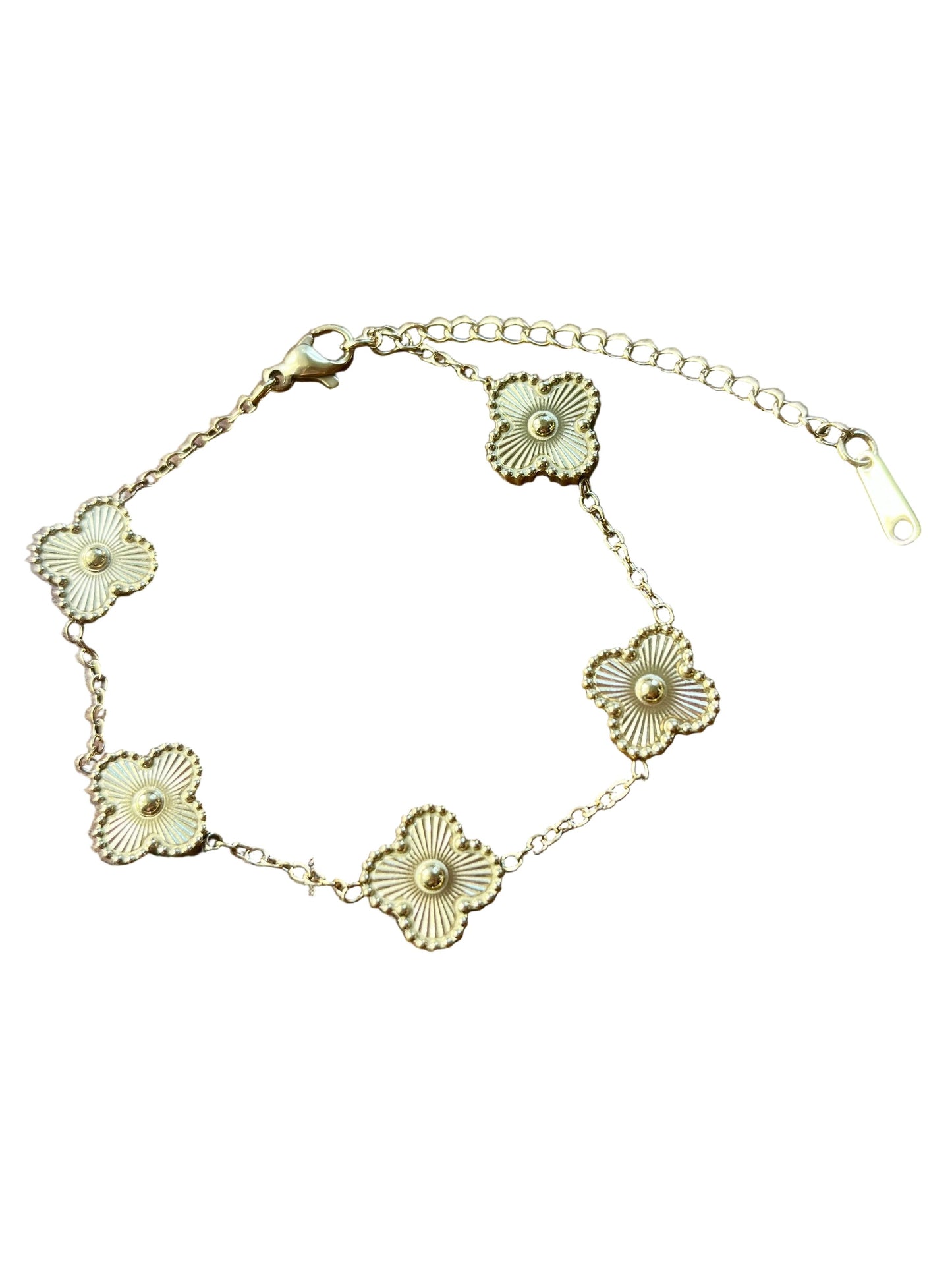 A gold-tone chain bracelet with five textured flower motifs, laid out on a brown wooden surface.