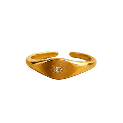 A gold adjustable ring with a central star-shaped cutout and a small clear gemstone.