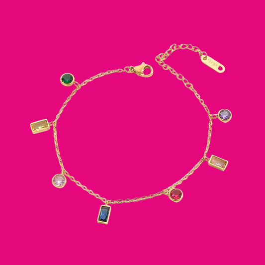 Gold bracelet with colorful gemstones on a pink background