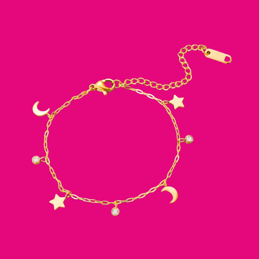 Gold bracelet with star and moon charms on a pink background