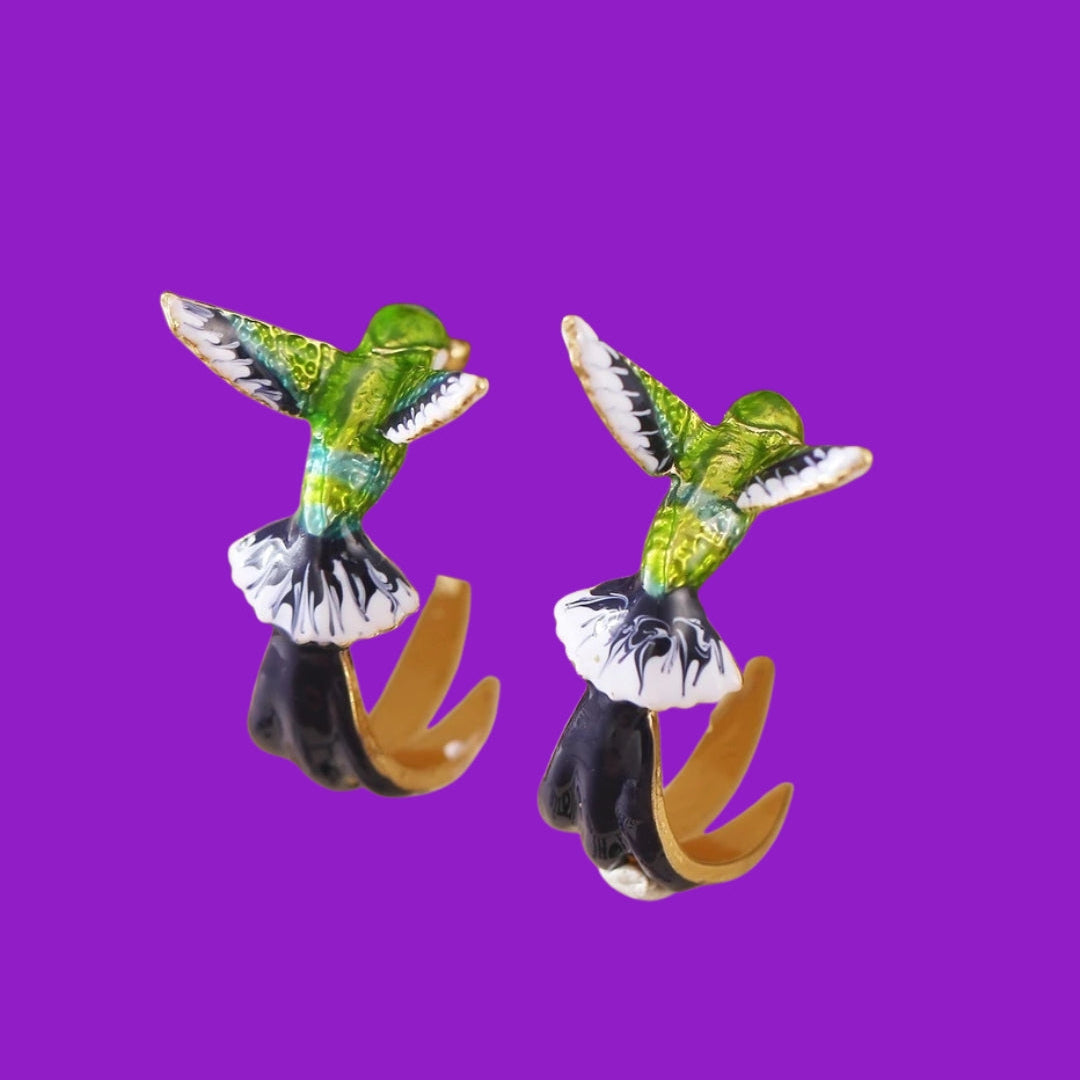 Pair of hummingbird-shaped earrings on a purple background