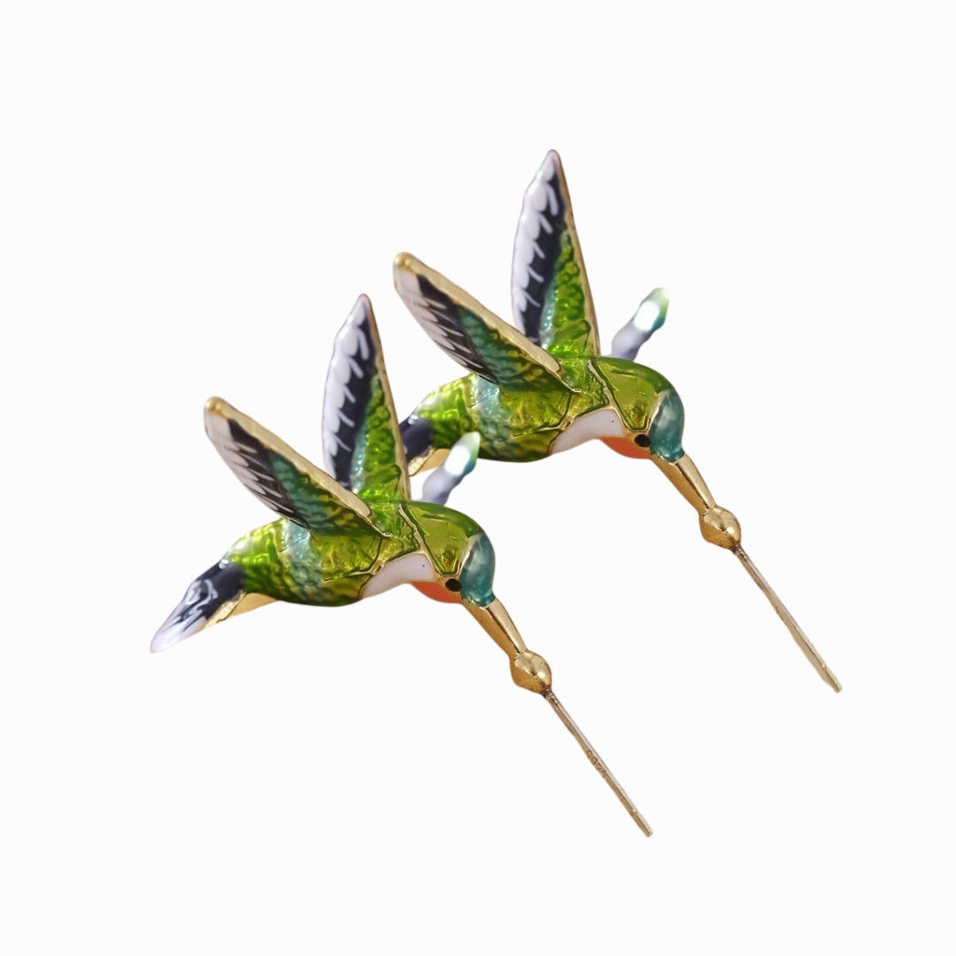 Two green and gold hummingbird figurines on a white background