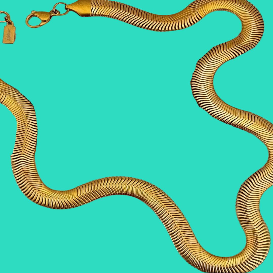 Gold snake-shaped necklace on a turquoise background