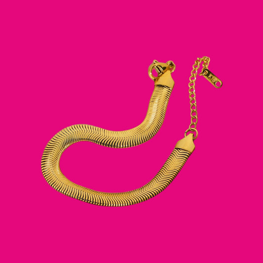 Gold snake-shaped bracelet on a pink background