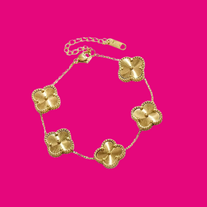 Gold bracelet with clover-shaped charms on a pink background