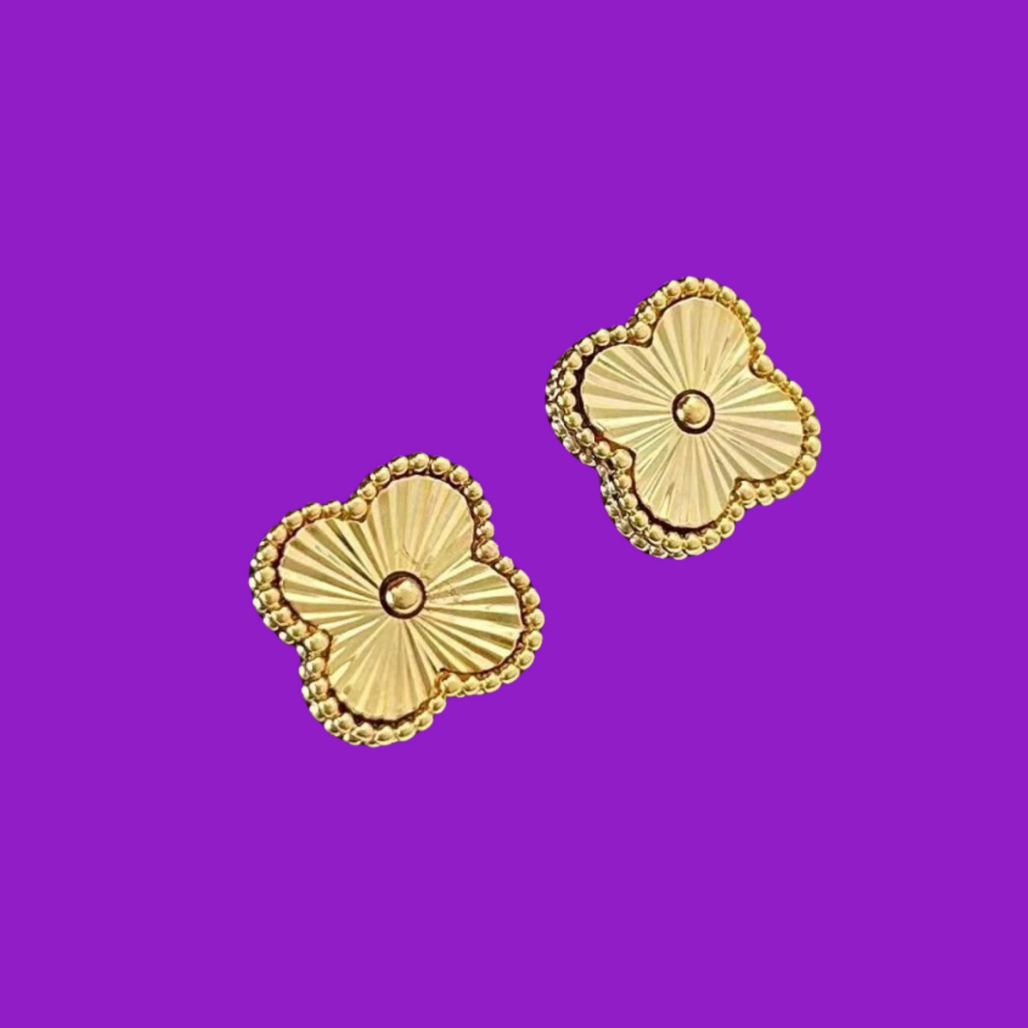 Gold floral earrings on a purple background