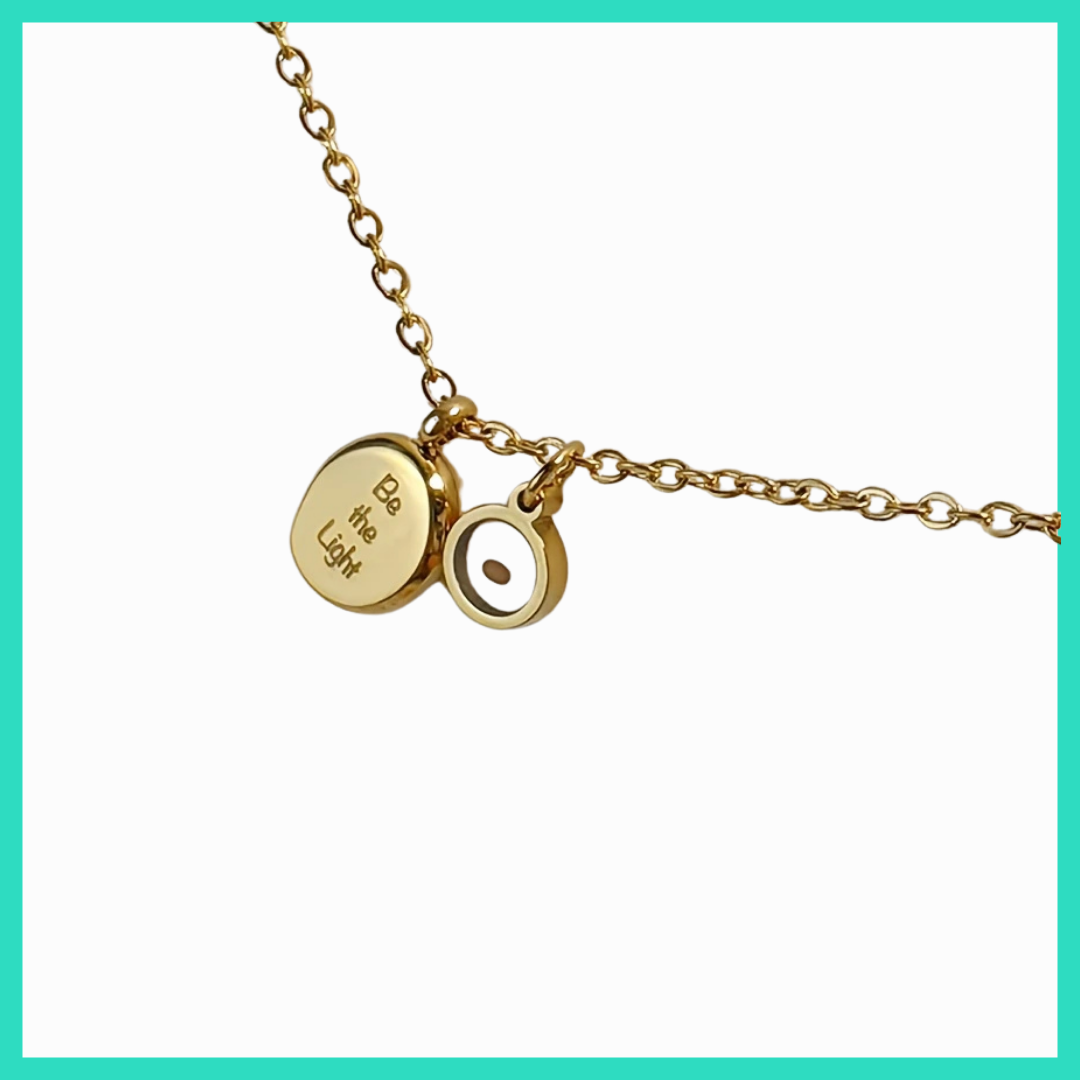 Gold necklace with two charms on a white background