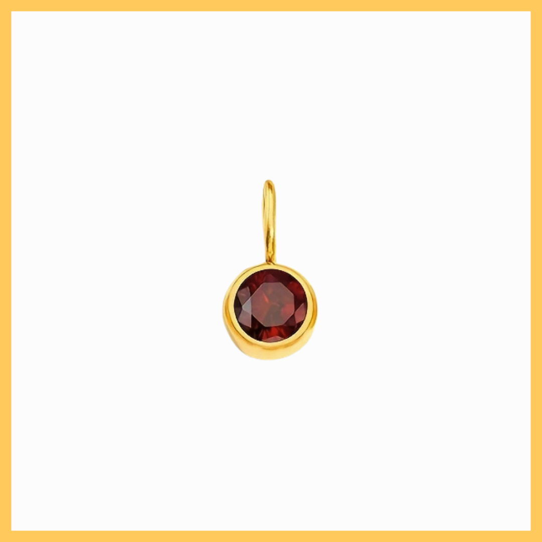 Gold pendant with a red gemstone on a white background
