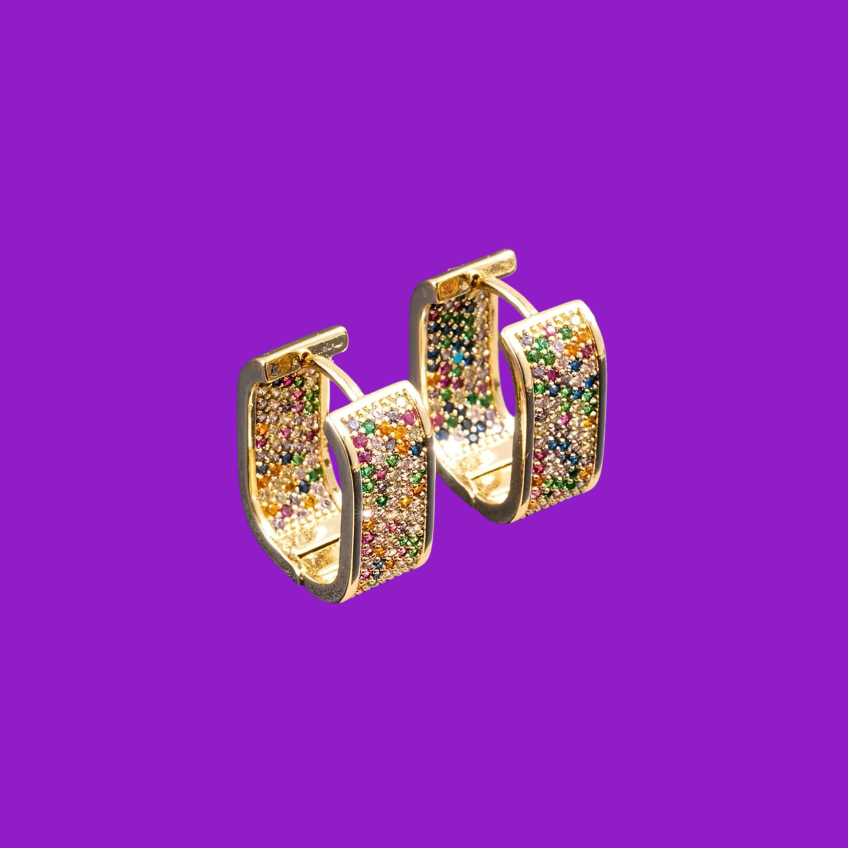 Gold hoop earrings with multicolored gemstones on a purple background