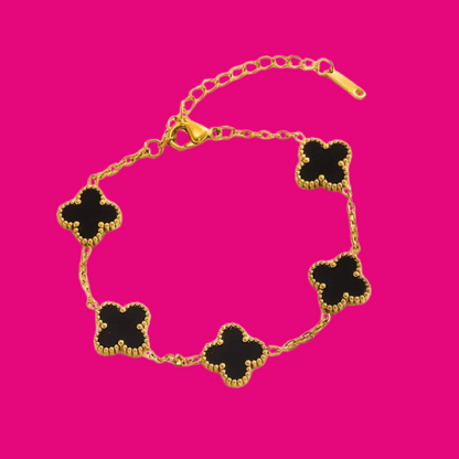 Gold bracelet with black clover-shaped charms on a pink background
