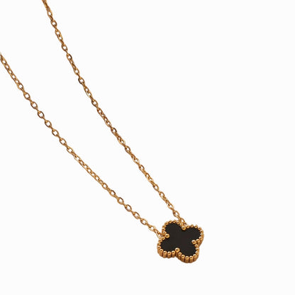 Gold necklace with a black clover-shaped pendant on a white background