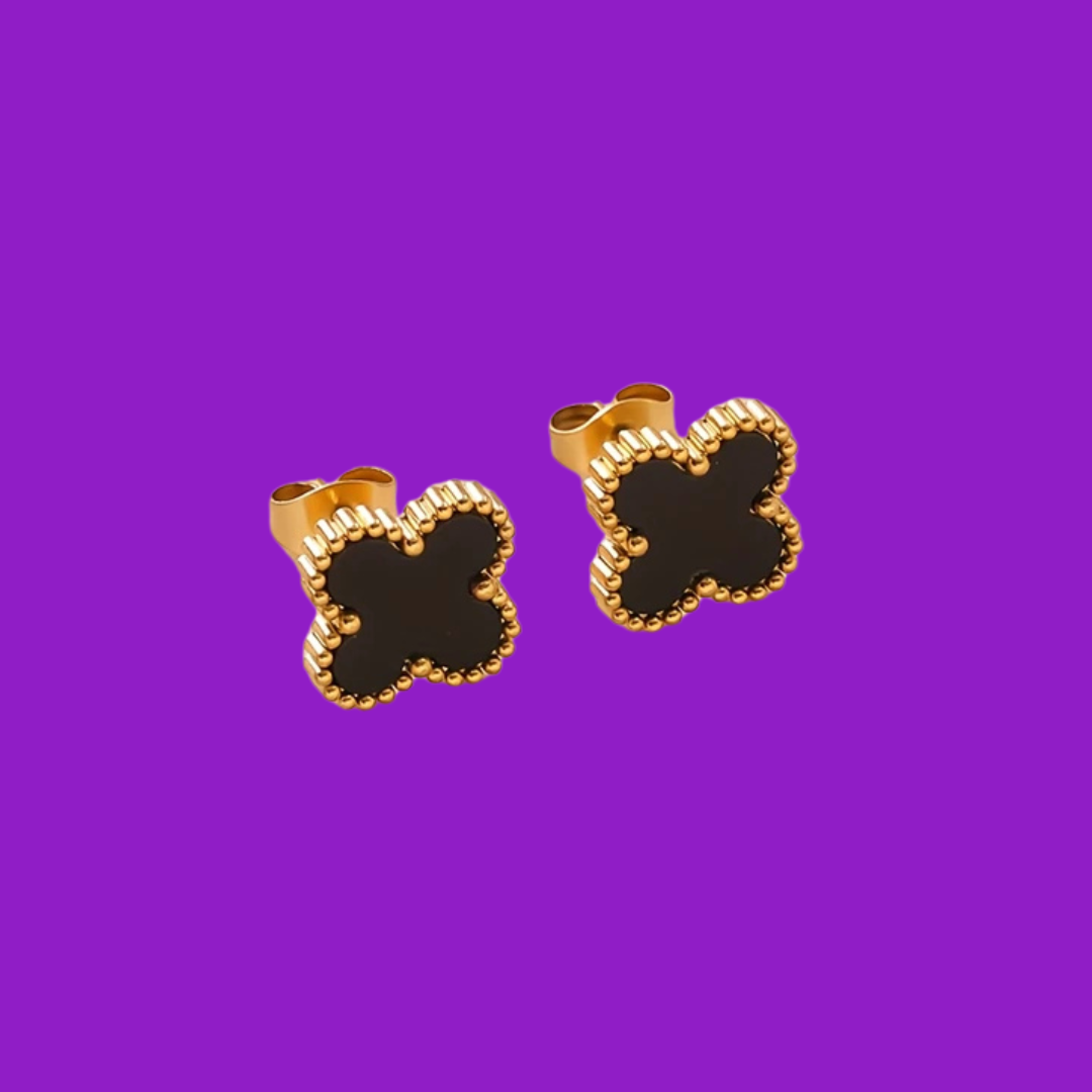 Gold and black clover-shaped earrings on a purple background