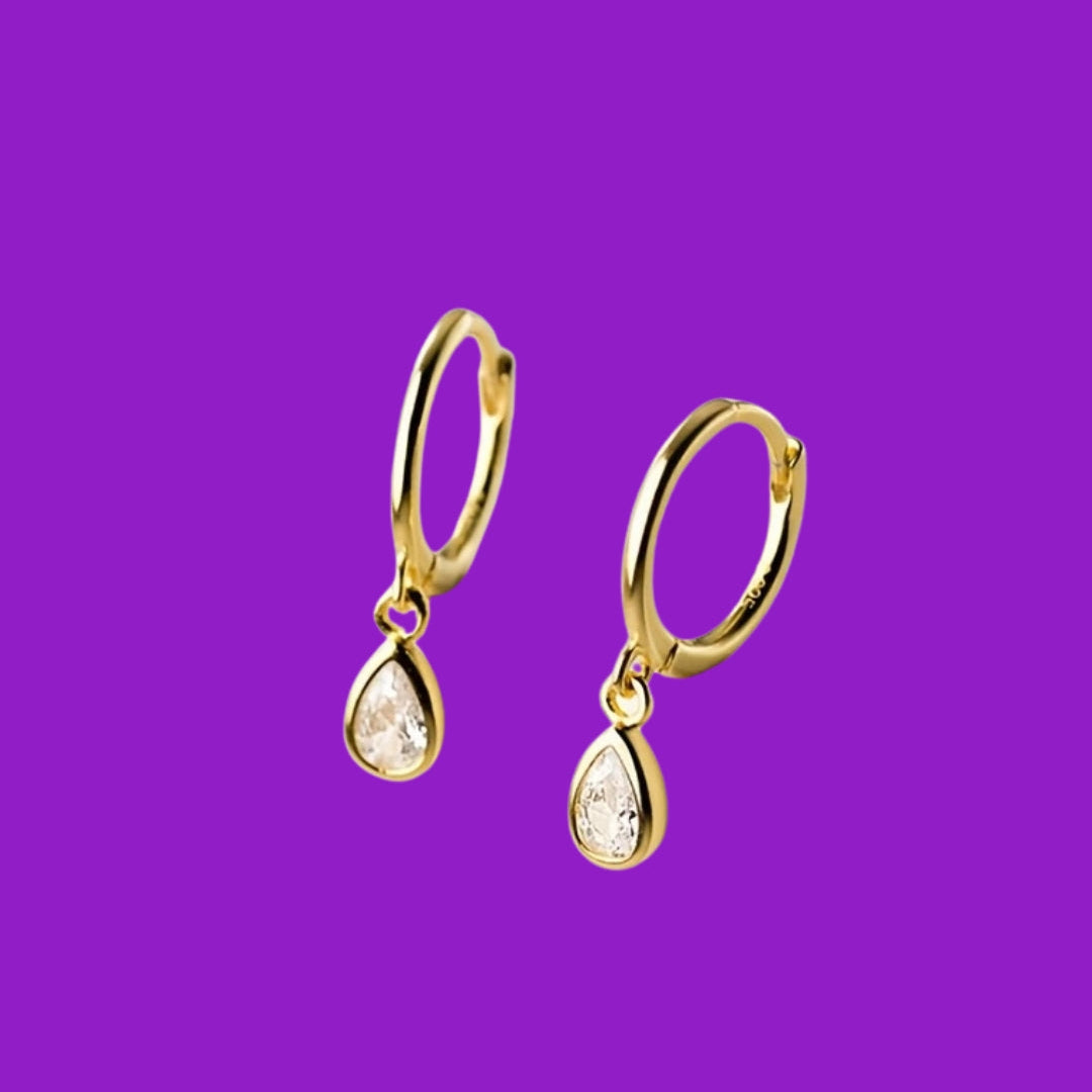Gold hoop earrings with teardrop-shaped charms on a purple background