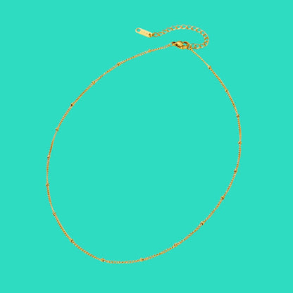 Gold necklace on a turquoise background