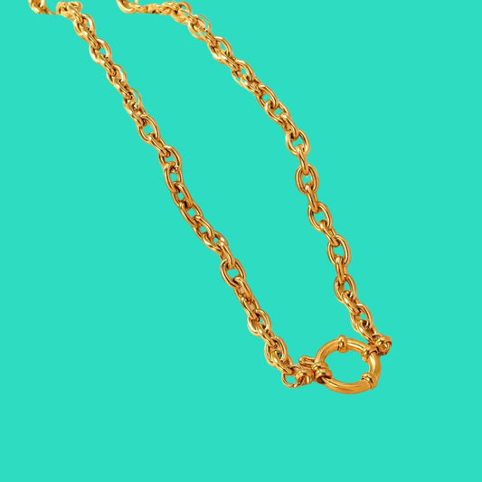 Gold chain necklace on a turquoise background