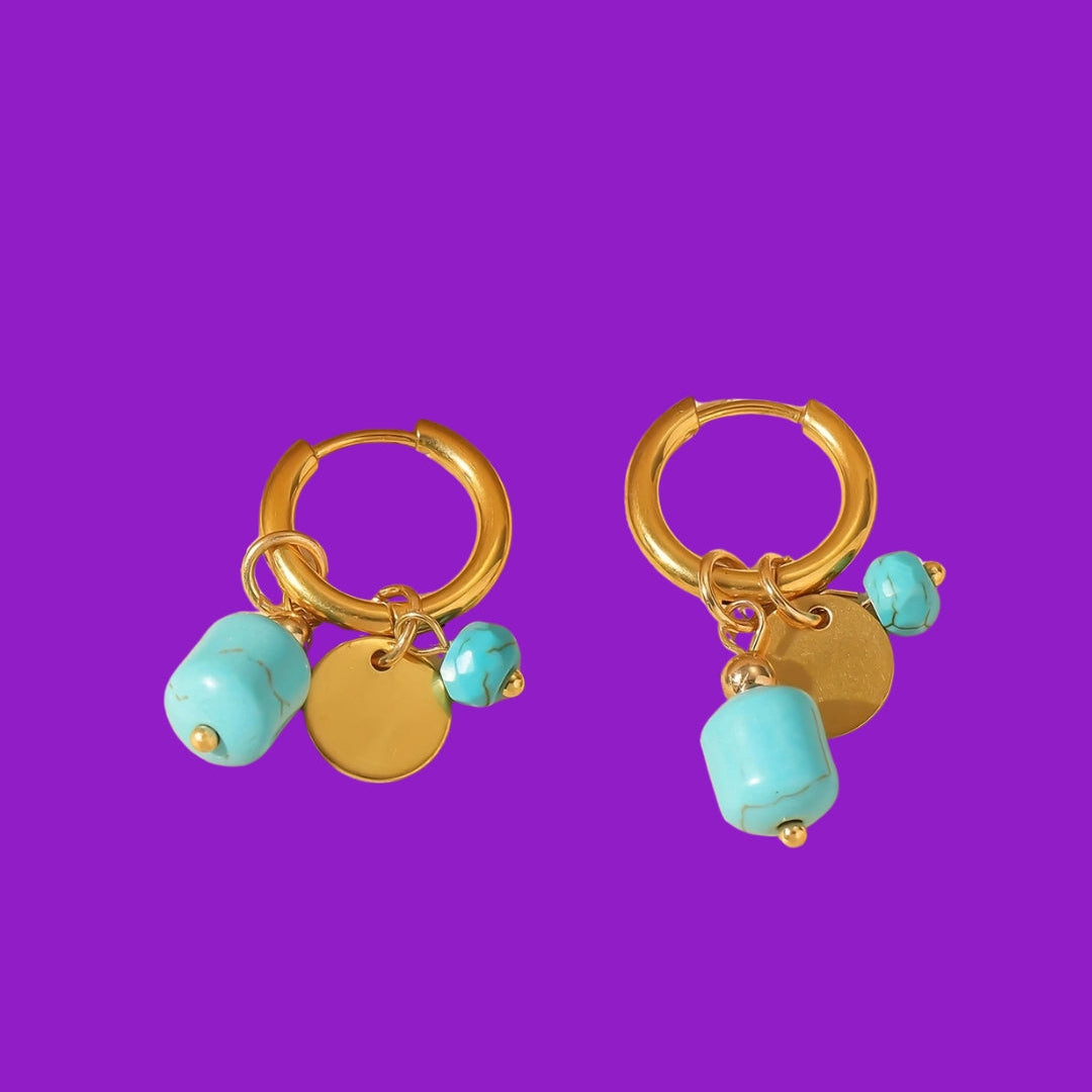 Gold hoop earrings with turquoise beads on a purple background