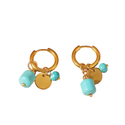 Gold hoop earrings with turquoise beads on a purple background