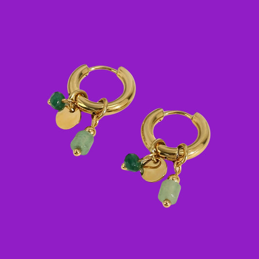Gold hoop earrings with green beads on a purple background