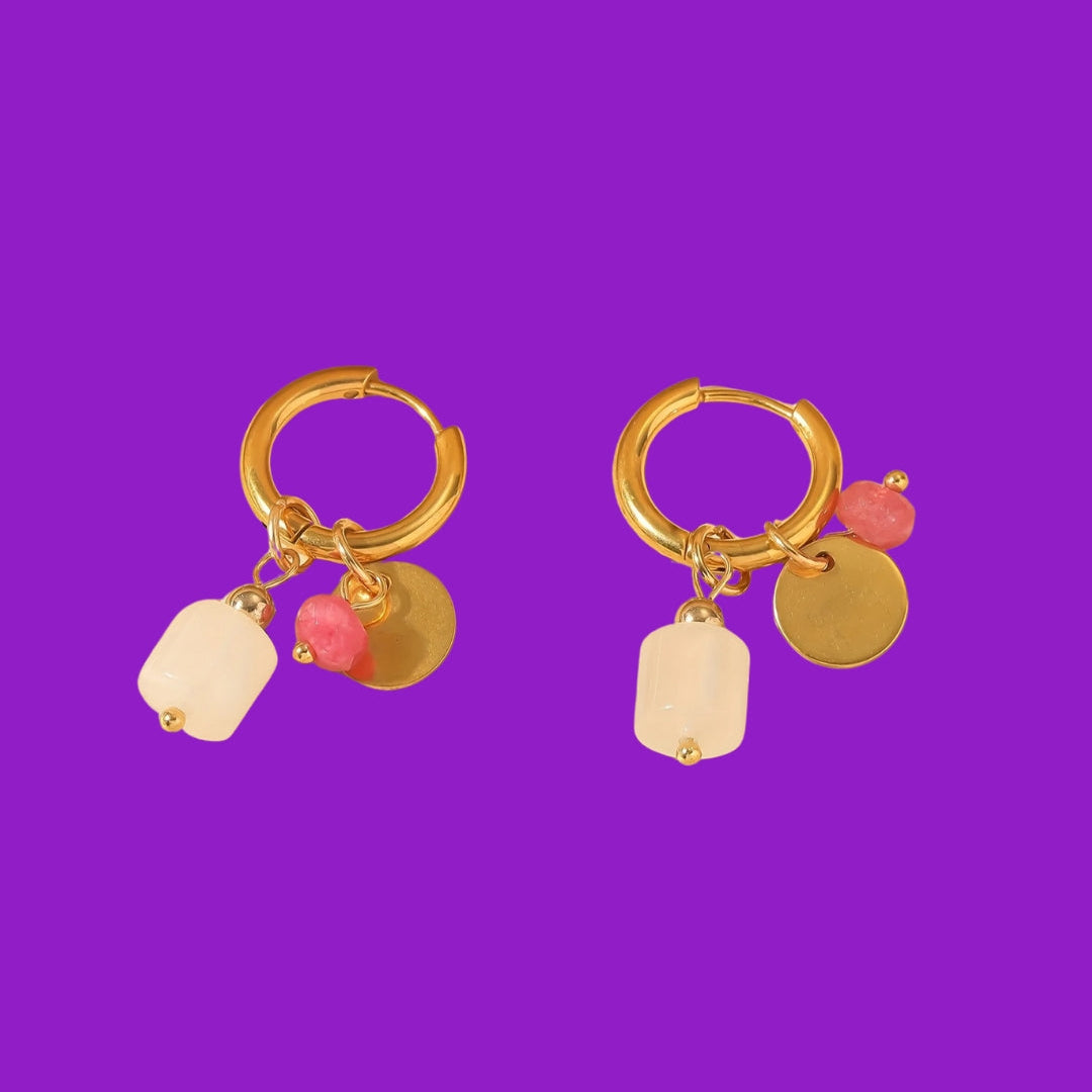 Gold hoop earrings with colorful charms on a purple background