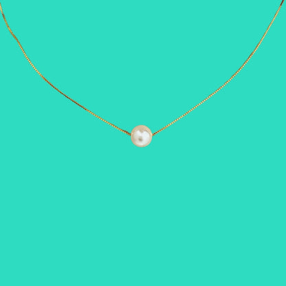 Gold necklace with a single pearl pendant on a teal background