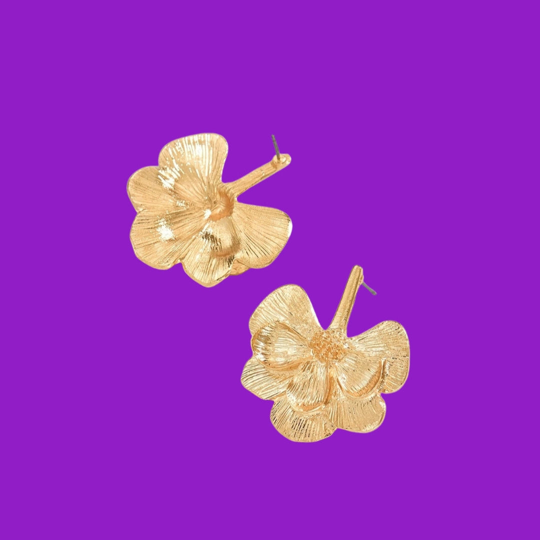 Gold floral earrings on a purple background
