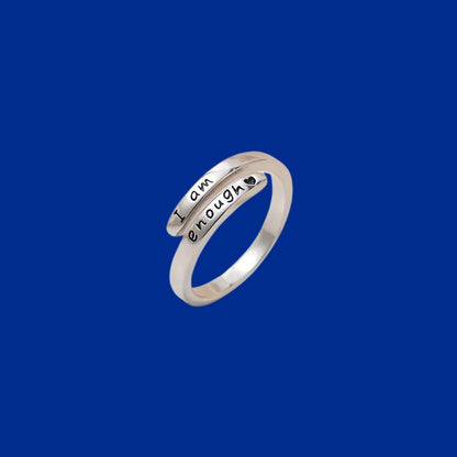 Silver ring with 'I am enough' engraving on a blue background