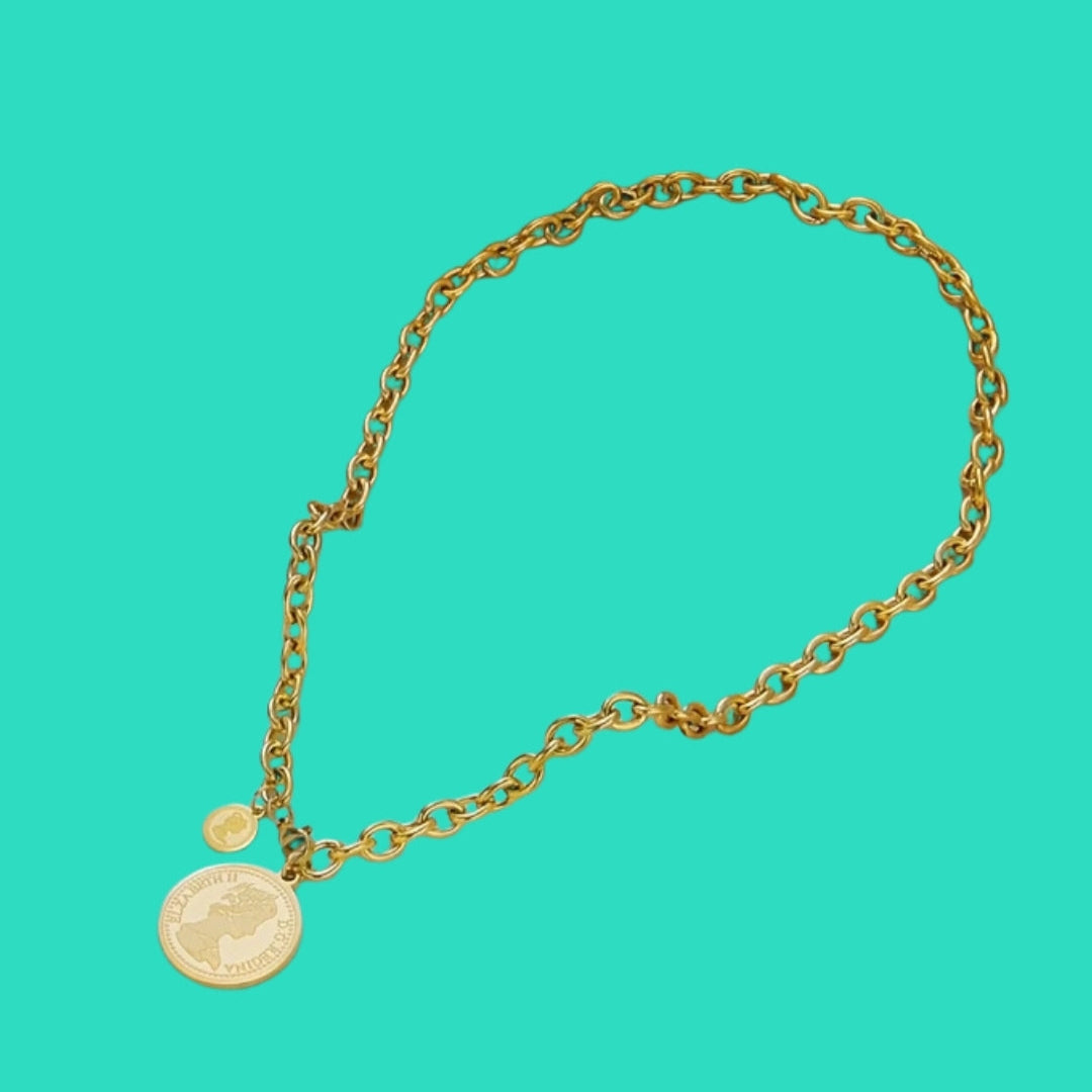 Gold chain bracelet with a round charm on a teal background