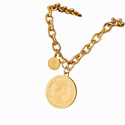 Gold chain bracelet with a coin charm on a white background