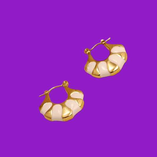 Gold and white hoop earrings on a purple background