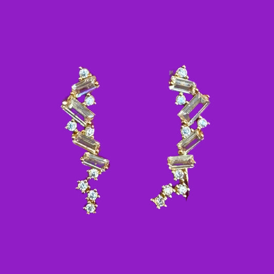 Gold and crystal earrings on a purple background