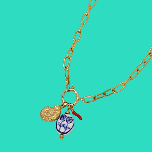 Gold chain necklace with charms on a turquoise background