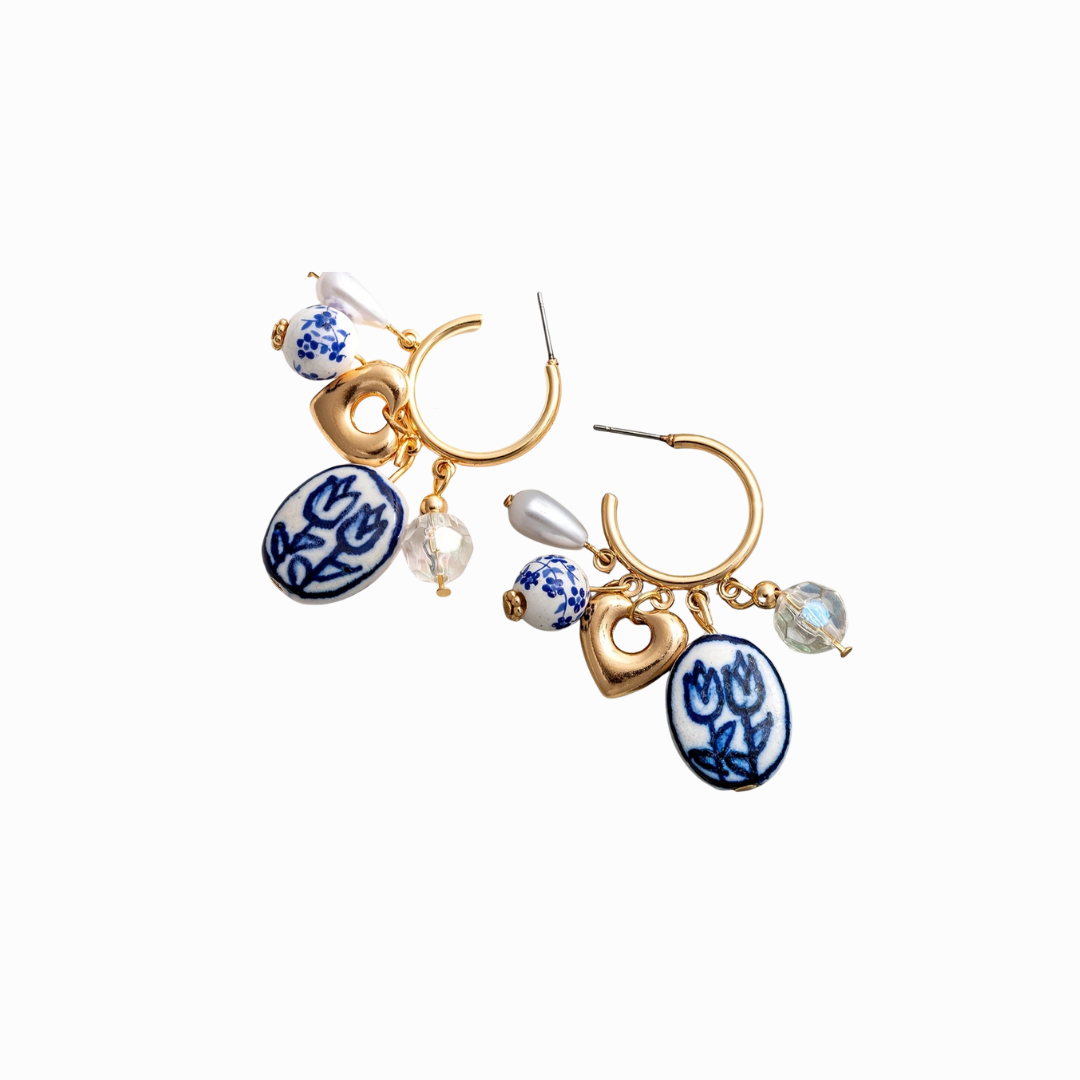 Pair of gold hoop earrings with blue and white ceramic charms on a white background