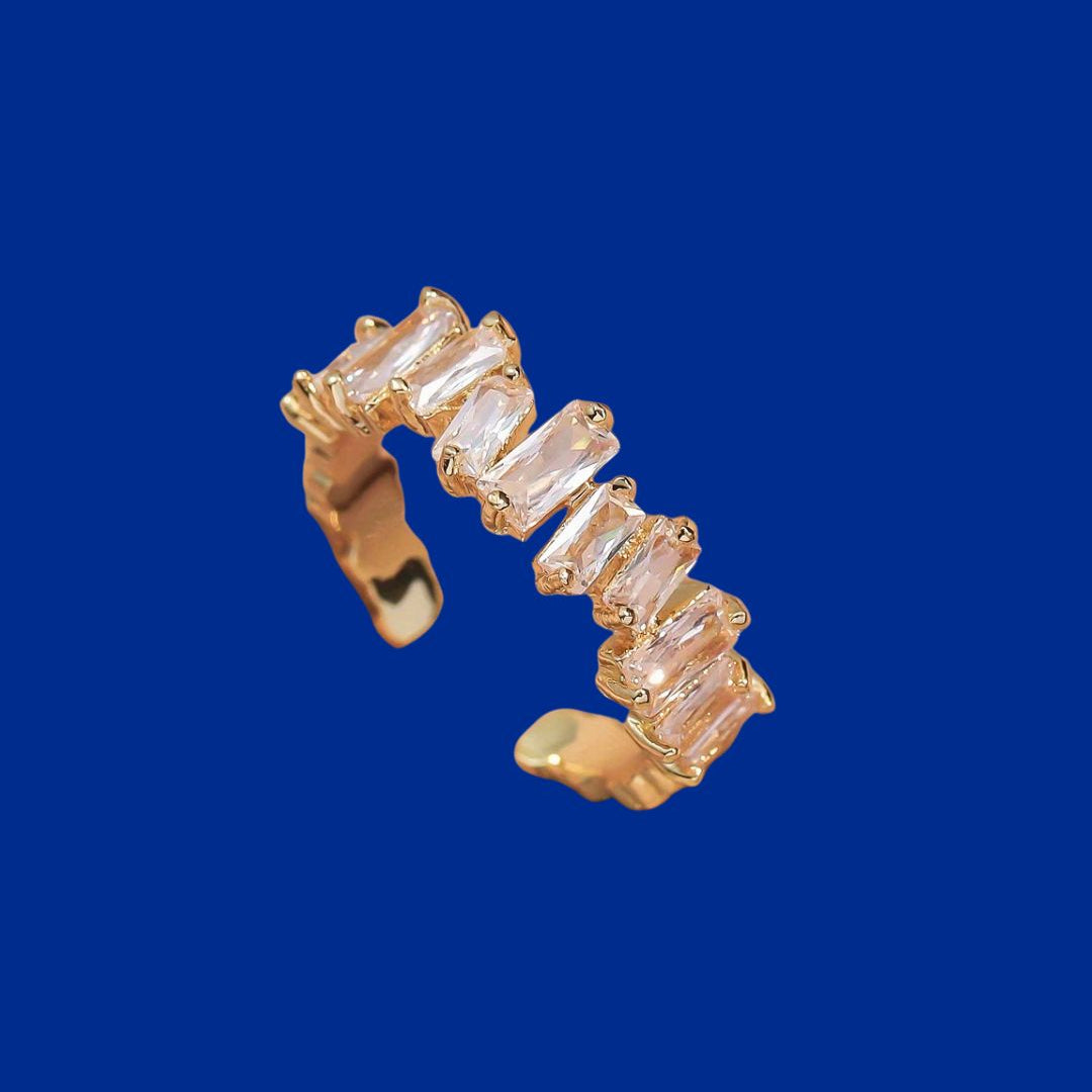 Gold ring with baguette-cut gemstones on a blue background