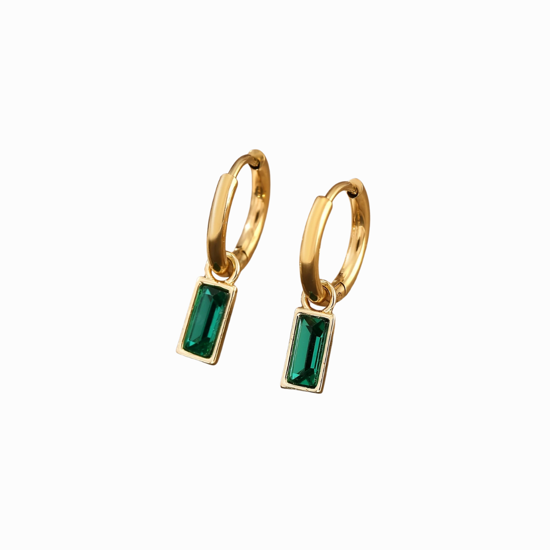Gold hoop earrings with green gemstones on a white background
