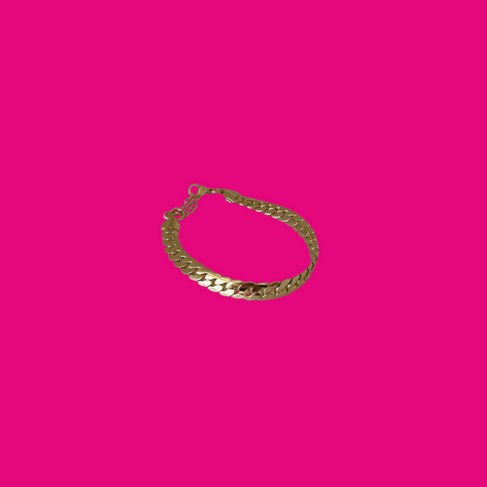 Gold chain bracelet on a pink background