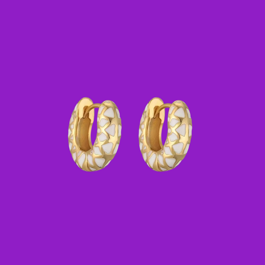 Gold hoop earrings with a textured pattern on a purple background