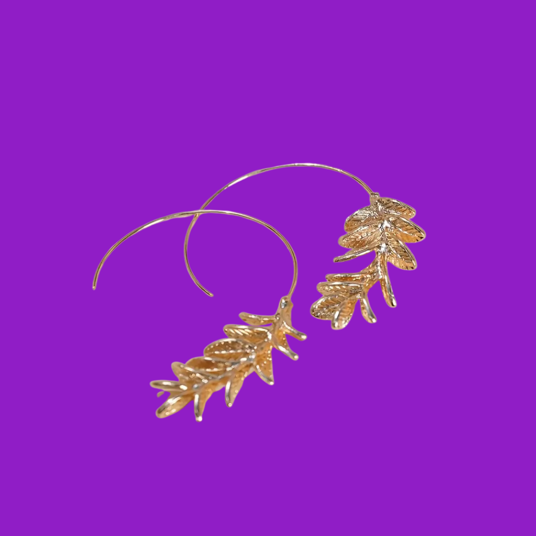 Gold leaf-shaped earrings on a purple background