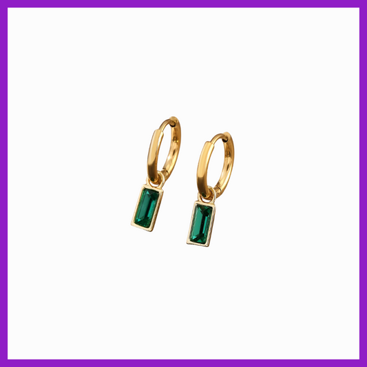 Gold hoop earrings with green gemstones on a white background
