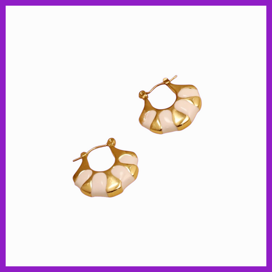 Gold hoop earrings with a white pattern on a white background