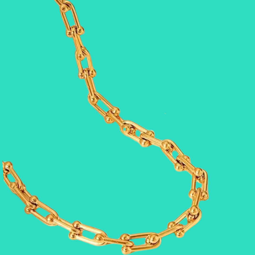 Gold chain necklace on turquoise background.