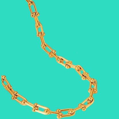 Gold chain necklace on turquoise background.