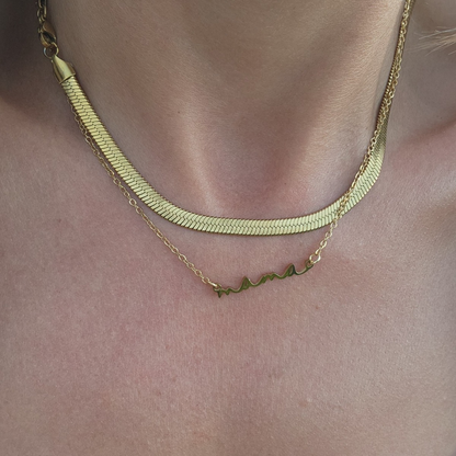 Two gold necklaces on a person's neck