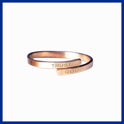Rose gold ring with 'TRUST GOD' engraving on a white background